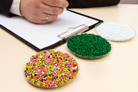 Businessman inspects plastic pellets for industry. Plastic raw materials in granules . Polymer, plastic resin. The dye in the granules of polypropylene and polyethylene.の写真素材