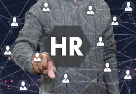 An elderly pensioner chooses HR, human resources in the business on the touch screen on blur office background.The concept of finding talented and skilled personnel.の写真素材