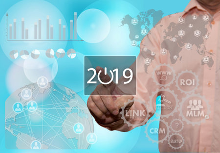 An elderly businessman chooses 2019 year on the touch screen with a blur office background...