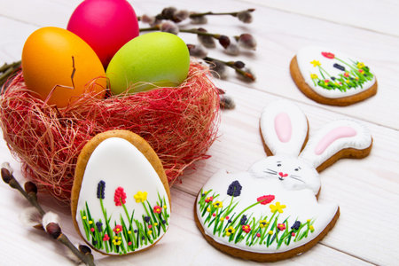 Gingerbread Easter set painted eggs and willow twig on white wooden background.  Easter Bunny and...