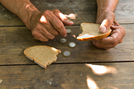 Hands the poor old man's, piece of bread and change, pennies on wood background.の写真素材