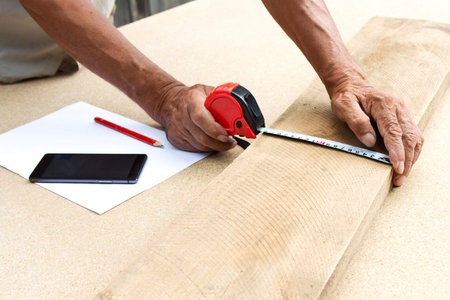 Carpenter inspect the quality of the material and calculate the required quantity for production .Manufacturing of furniture from a natural tree.Employee Uses technology to benefitの写真素材