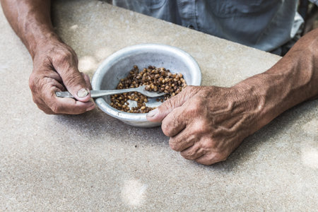 Hungry. Poor old man's hands an bowl of porridge . Selective focus. Poverty in retirement. Alms