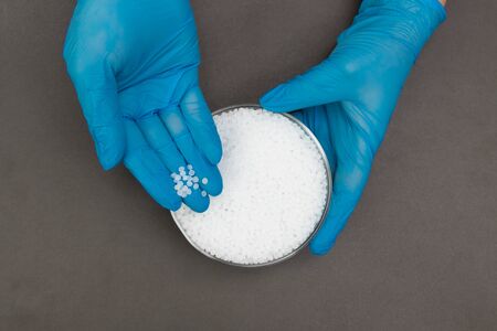 Plastic granules . Polypropylene, polyethylene pellets in hands with gloves. Quality control of plastic in the laboratory in productionの写真素材