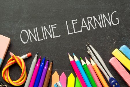 Online learning in Quarantine inscription on the background of a blackboard and school supplies .Homeschooling during quarantine. At home, study in the event of an outbreak of the Covid-19 coronavirus pandemic.の写真素材