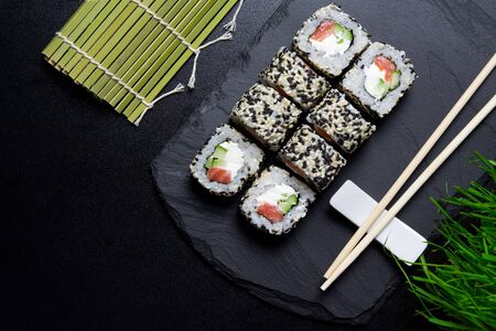 Sushi VENICE rolls with sesame and salmon on a background of green grass and matting on a Board made of stone. Sushi food photo for menu.The view from the topの写真素材