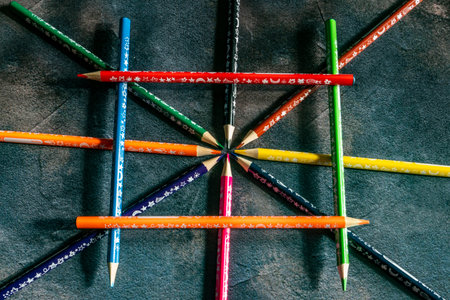 Colorful pencils on grey paper background. School supplies in colors of rainbow on blackboard. Kids stationery with black copy space. Back to school backdrop.の写真素材