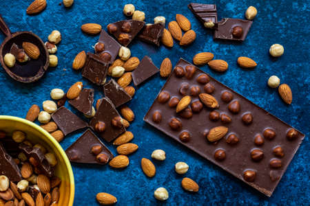 Chocolate chunks with hazelnuts isolated on blue backgroundの写真素材