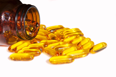 Fish oil capsules in a glass bottle isolated on white backgroundの写真素材