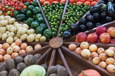 Assortment of fresh organic vegetables on wooden shelves at the farmers market. Different raw vegetables apples, eggplant, tomato, cucumber, beet, pepper, potatoes, cabbage, pumpkin, onion.の写真素材