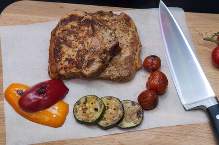 Grilled pork steak and baked vegetables on wooden board. Top view.の写真素材