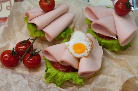 Sandwich with fried eggs, sausage, lettuce and sauce. Fried eggs and sausage sandwich in cafeteria.の写真素材