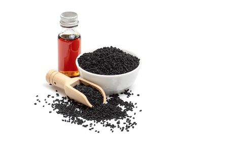 Black cumin seeds in bowl and essential oil in glass bottle. Nigella sativa isolated on white background.の写真素材