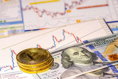Golden bitcoin coins on financial charts and us dollar background. Concept of cryptocurrency exchange and financial investment.の写真素材
