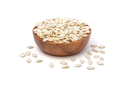 Pumpkin seeds in shell isolated on white background. Unpeeled pumpkin seeds in wooden bowl top view.の写真素材