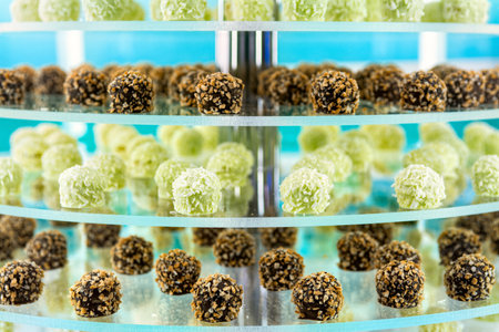 Various pastries on multi-tiered glass shelves in pastry shop or cafe.の写真素材