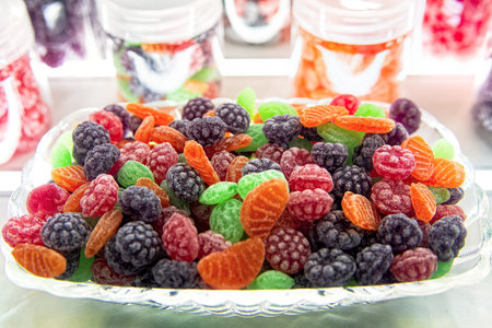 Pile of colorful fruit hard candy in the shape of berries and fruits in glass bowl. Natural sweets...