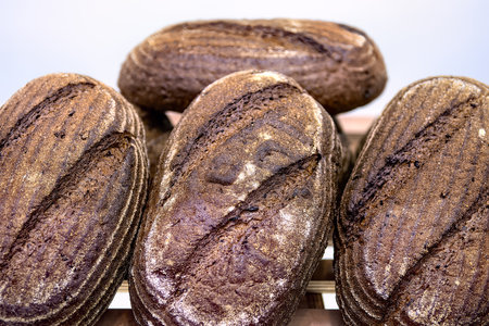 Loaves of dark rye bread on shelf in bakery. Sale of baked goods in the store.の写真素材