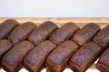 Loaves of dark rye bread on shelf in bakery. Sale of baked goods in the store.の写真素材