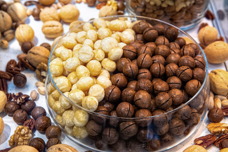 Macadamia nuts in glass bowl among other various nuts in health food store display case. Mixed nuts...