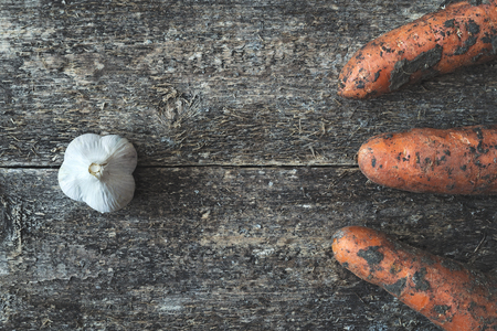 Organic garlic and dirty carrot whole on the wooden rustic background, top view. Vegetable.の写真素材
