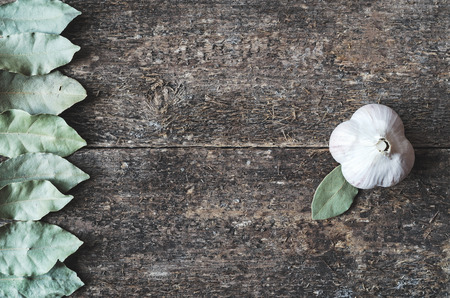 Dry bay leaf and garlic on the wooden rustic background, top view. Bay leaf and garlic background.の写真素材