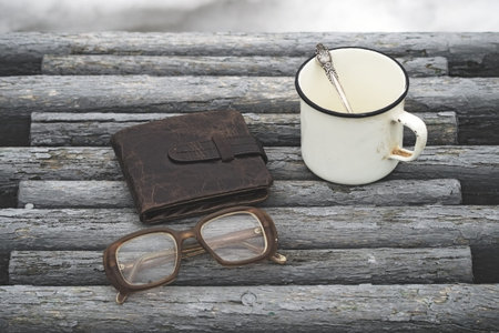 Old glasses and hot drink on a park bench with natural background toned with a retro vintage filter....
