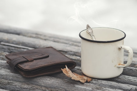 Vintage purse and old mug with a hot drink on a park bench with natural background in the outdoors....