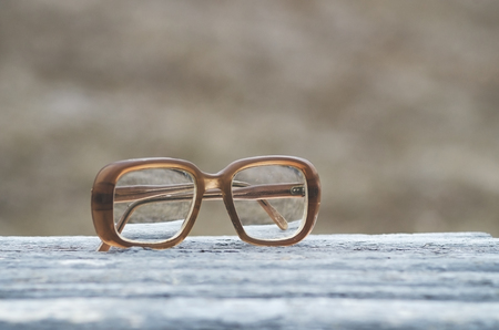 Old glasses on a park bench or table with natural background toned with a retro vintage filter app or action effect.の写真素材