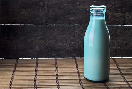 Old style bottle of fresh milk on a rustic wooden table.の写真素材