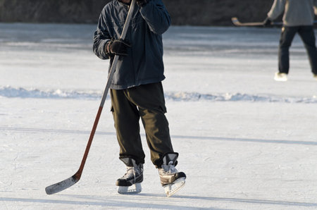 Hockey player practising on a frozen pond outdoor. People playing amateur hockey. Winter playing,...