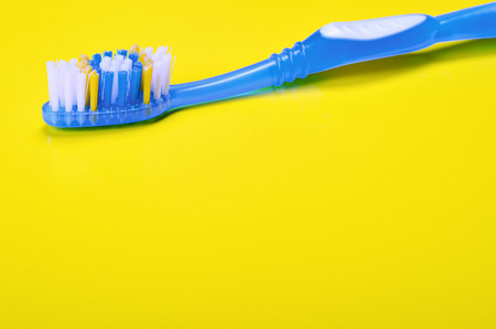 Close-up of colorful blue toothbrush on yellow background. Copyspace.の写真素材