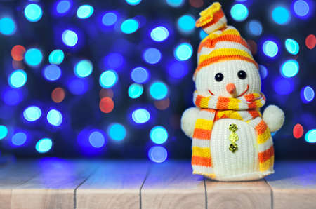 Christmas funny decorative snowmen on wooden board on bokeh garland lights background Christmas with copy space. Happy Christmas still life with funny decorative snowman on the garland lights background. Magic snowfall in lantern light. Selective focus.の写真素材