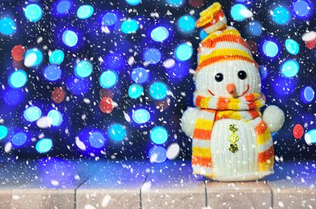 Christmas funny decorative snowmen on wooden board on bokeh garland lights background Christmas with copy space. Happy Christmas still life with funny decorative snowman on the garland lights background. Magic snowfall in lantern light. Selective focus.の写真素材