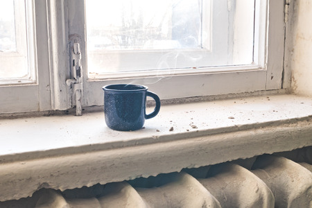 Old mug of hot tea or coffee on vintage windowsill. Retro style, selective focus.の写真素材