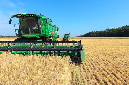 Kazanka, Ukraine - July 11: John Deere Combine Harvester T670 and Tractor 8370R Tractor using a...