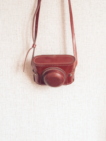 Vintage old rangefinder photo camera hanging on wall background. Vintage hipster theme color tone styles. Photography back to old school concept. Close up, copy space. Place for text.の写真素材