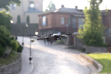 Drone quadcopter with digital camera flying above old city in blur backgroundの写真素材