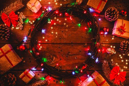 Wooden background with colored lights and stars. surrounded by gifts and cones. In the center there is space for the holiday message. Top view.の写真素材