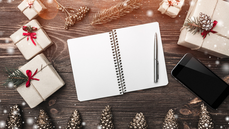 Horizontal brown wood background with fir cones, handmade handmade gifts and a space card for congratulations with winter, xmas, New Year and Christmas holidays. Effect of light blips and snowflakes. Top view.の写真素材