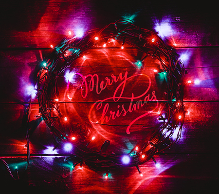 Wooden background with bright colored lights. with Merry Christmas center message. Top view. の写真素材