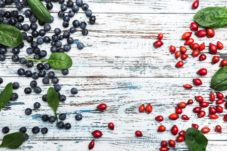 Blue and red berries with basil leaves on white wood background. Top view, space for writing, flat layの写真素材