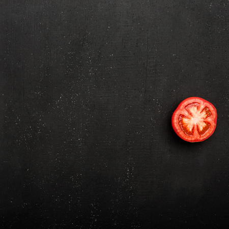 Tomato slice on black background. Vegetable concept, close-up viewの写真素材