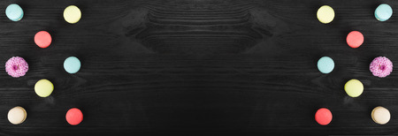 Colorful macarons arranged symmetrically, mirror effect on wooden table with copy spaceの写真素材