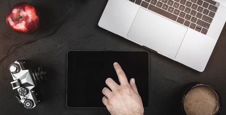 Man touching digital tablet with a black screen, working online at office desk with other items. Top viewの写真素材