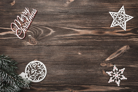 View from above of a Merry Christmas inscription and handmade tree toys on wooden background, greeting card with space for text writingの写真素材