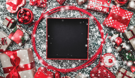 Red circle from decorative wands, with opened black Xmas present box, package and space for text writing inside, on gray, stone, marble background, greeting cardの写真素材