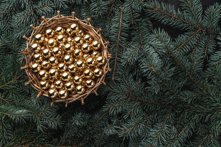 Winter background of fir branches. Basket with golden baubles. Christmas card. Top view. Xmas...