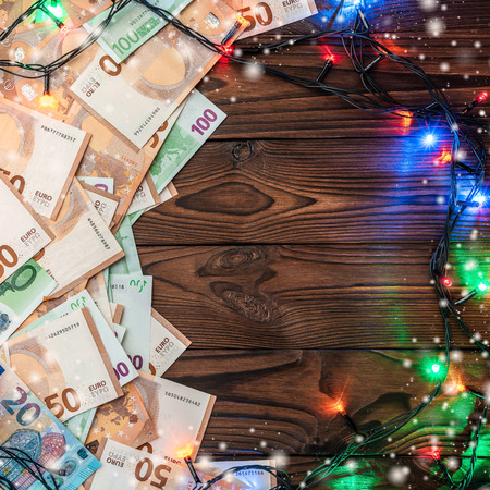 Wooden background, banknotes, gifts, fir branches, Christmas atmosphere. Top view. Space for your text. Xmas card.の写真素材