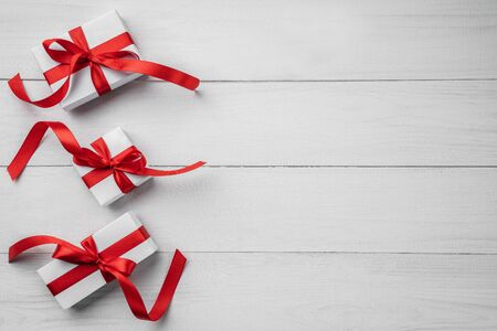 Christmas holiday background composition. Christmas gifts with red ribbon on white wooden table. Xmas and happy new year card. Top view, flat lay, copy space.の写真素材